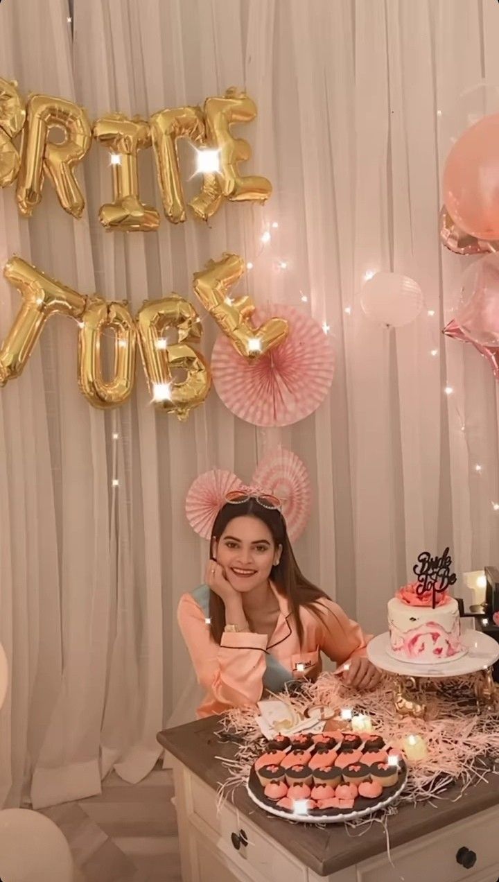 a woman sitting in front of a table with cake and balloons