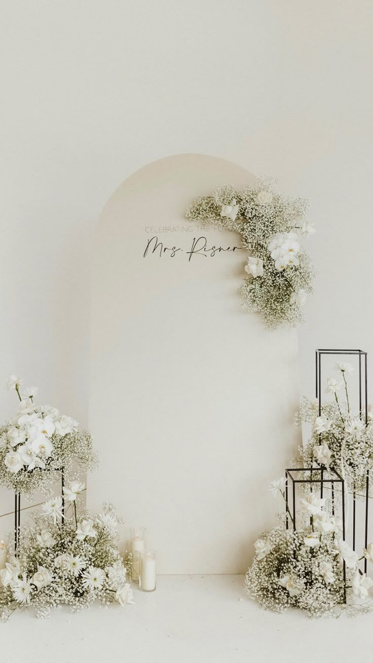 the wedding arch is decorated with white flowers and greenery