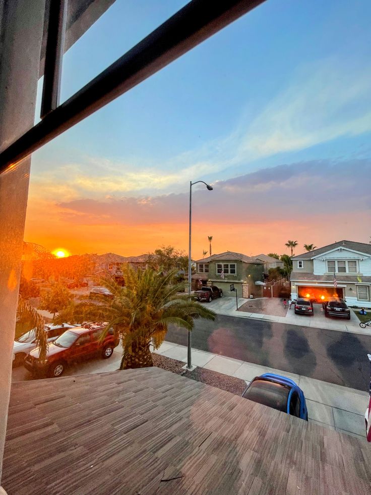 the sun is setting over some houses and cars