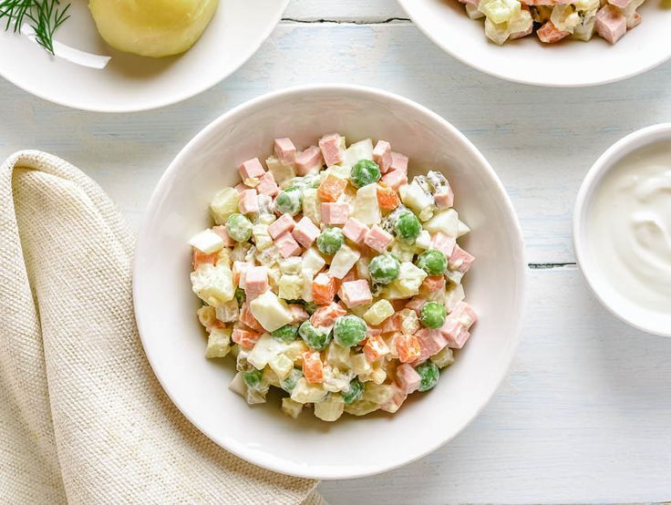 two bowls filled with potato salad on top of a white table