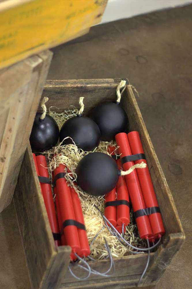 some black and red ornaments in a wooden box on the floor next to straw bales