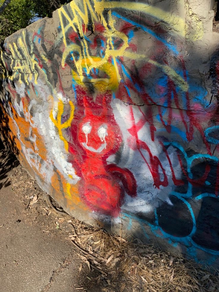 a wall covered in graffiti next to a sidewalk