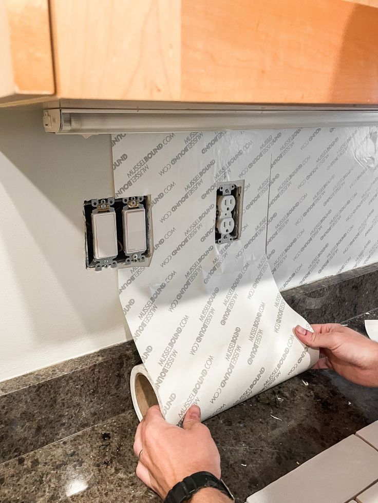 a person is wrapping up a roll of toilet paper on the kitchen counter with two rolls of toilet paper