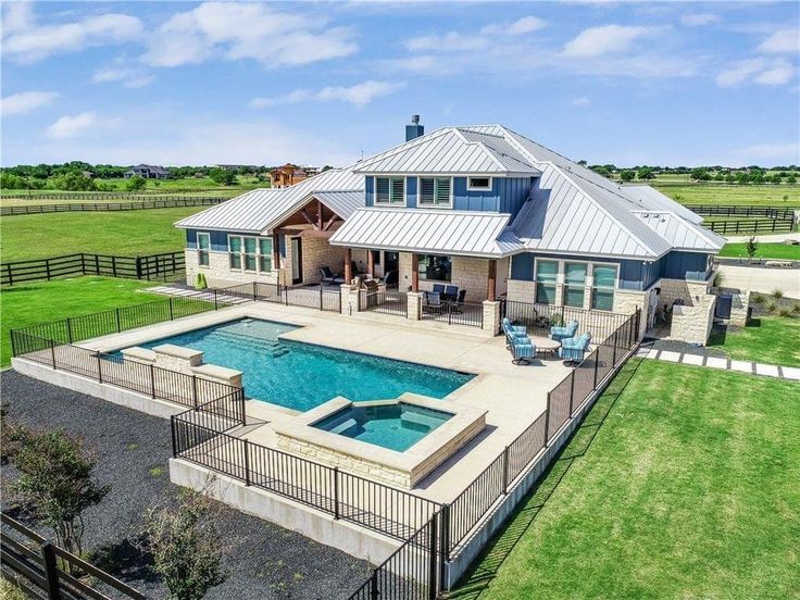 an aerial view of a house with a pool in the yard and fence around it