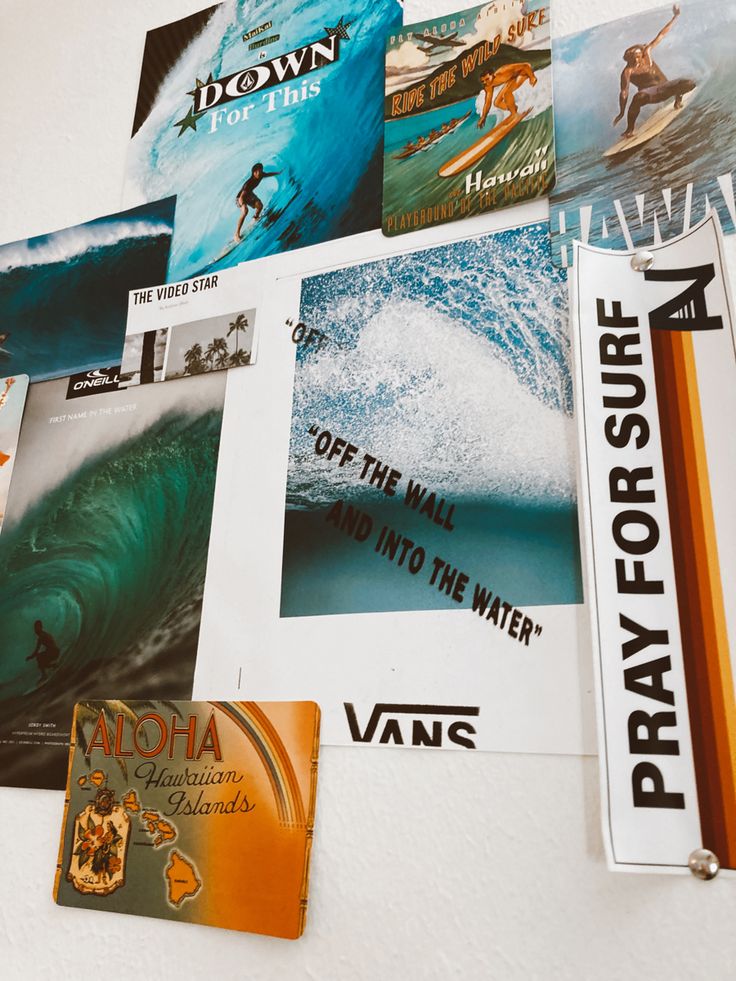 there are many posters on the wall above the bookshelf and below them is a surfboard