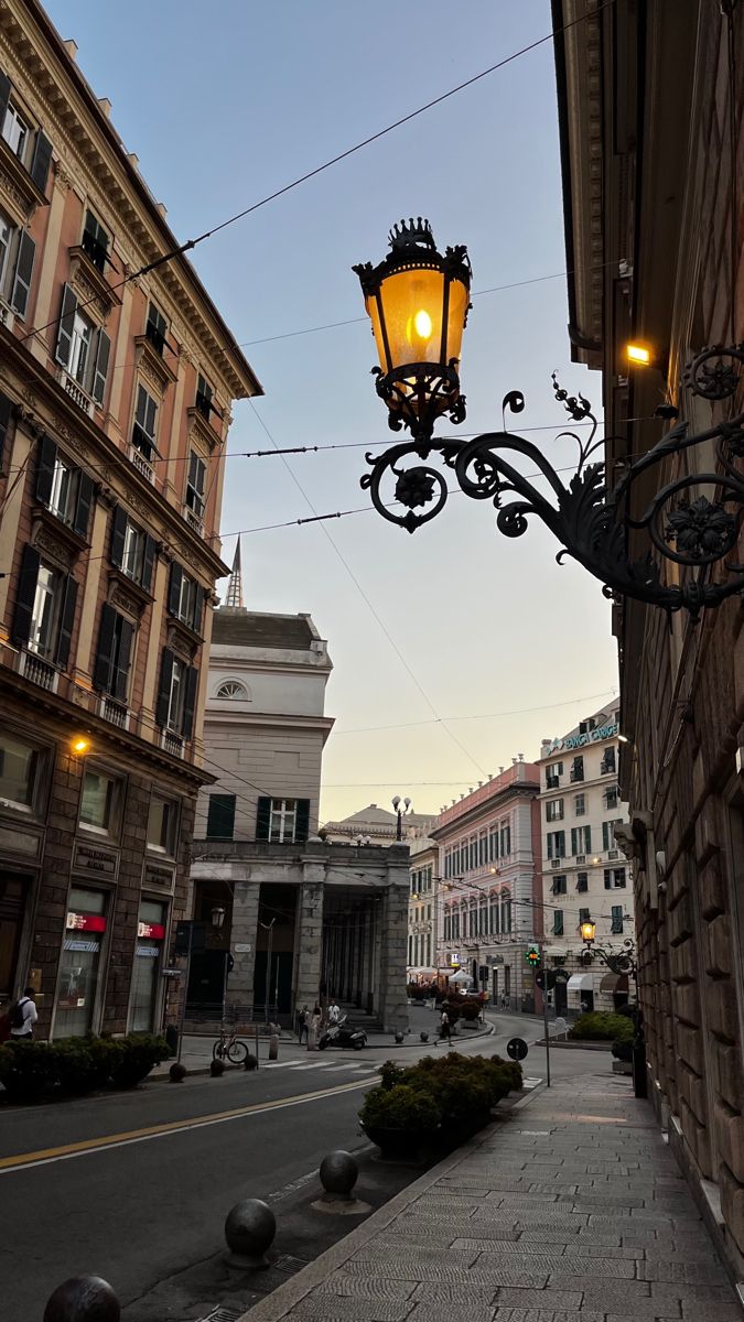 an old fashioned street light hanging from the side of a building in front of some buildings