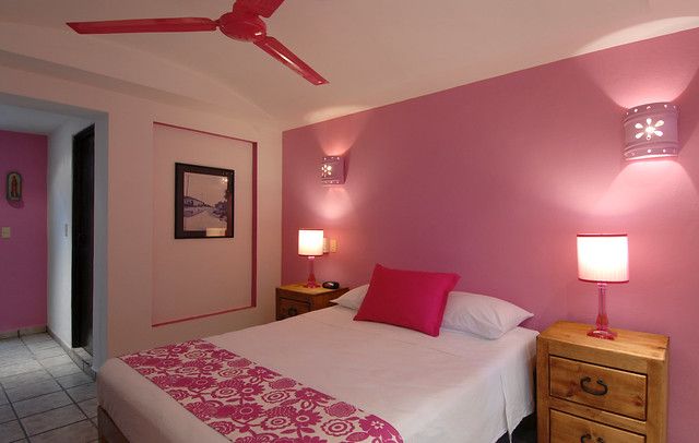 a bed room with a neatly made bed and pink walls