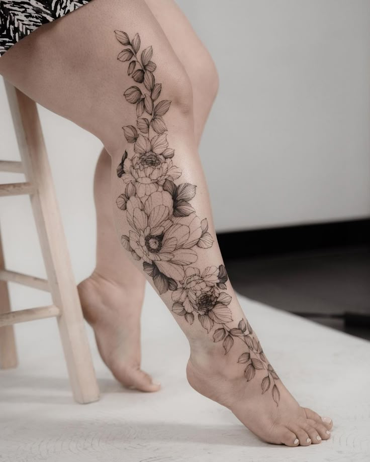 a woman's leg with flowers on it and a stool in the foreground