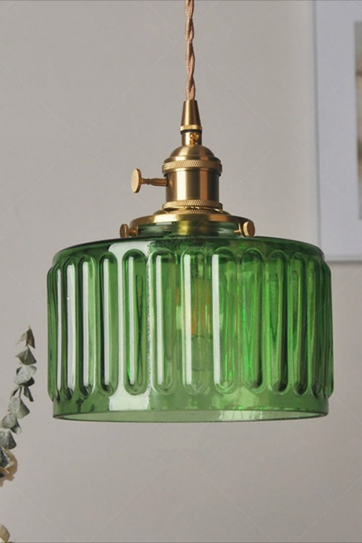 a green glass light hanging from a ceiling