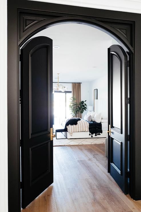 an open door leading to a living room with black doors and white couch in the background