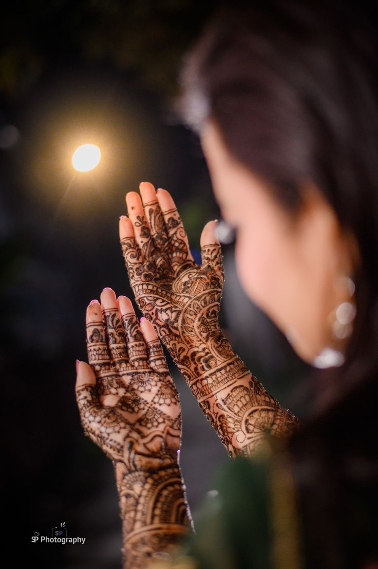 a woman holding her hands up in front of her face with hendi tattoos on it