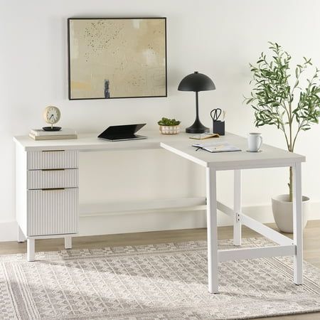 a white desk sitting on top of a wooden floor next to a potted plant