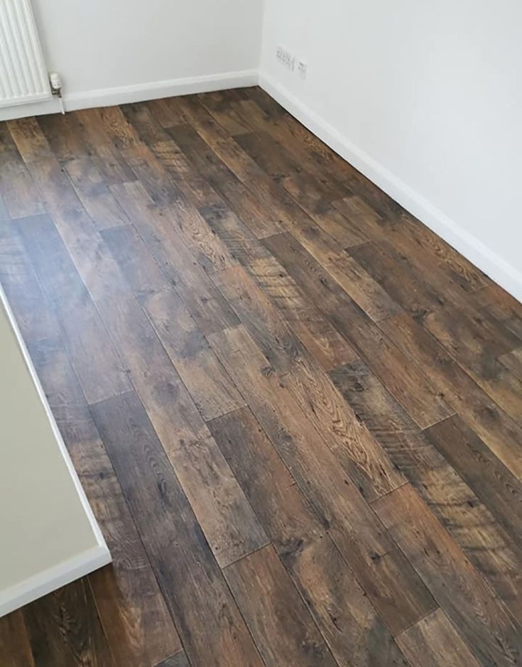 an empty room with wood flooring and white walls