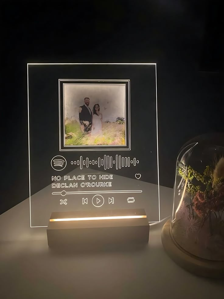 an illuminated photo frame with a glass dome underneath it and a small plant in the middle