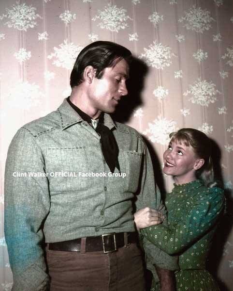 a man and woman standing next to each other in front of a wall with snowflakes on it