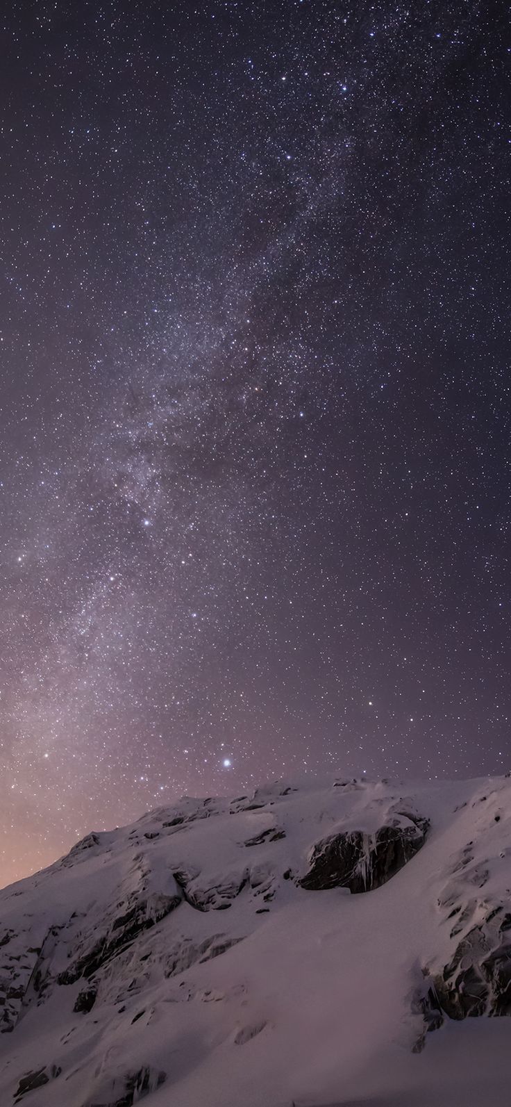 the night sky is filled with stars above snow covered mountains and rocks in the foreground