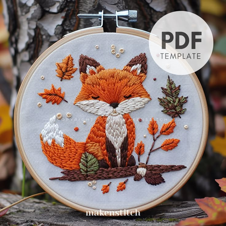 an embroidered fox sitting on top of a tree branch with autumn leaves around it's edges