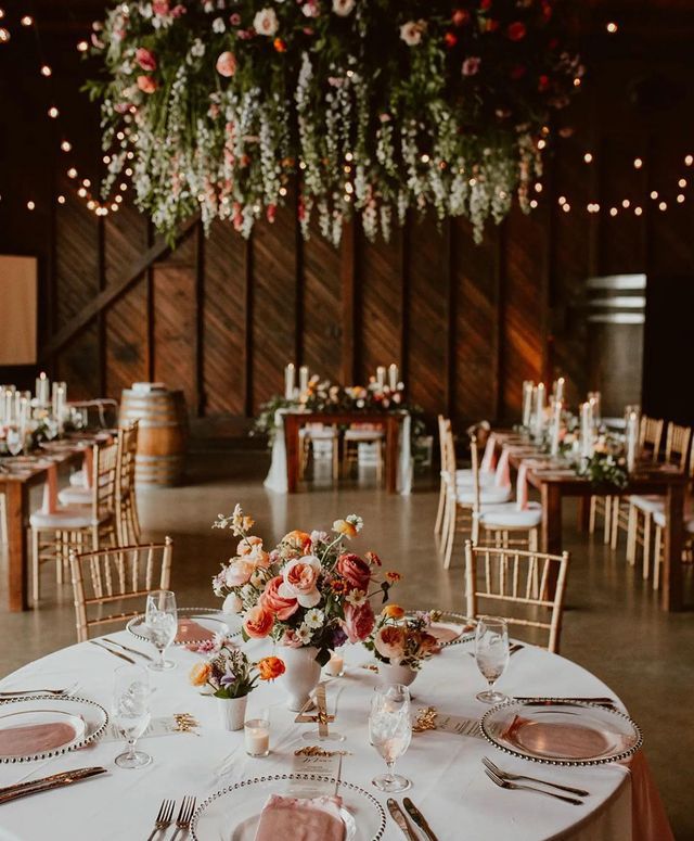 the tables are set up for a wedding reception with floral centerpieces and candles