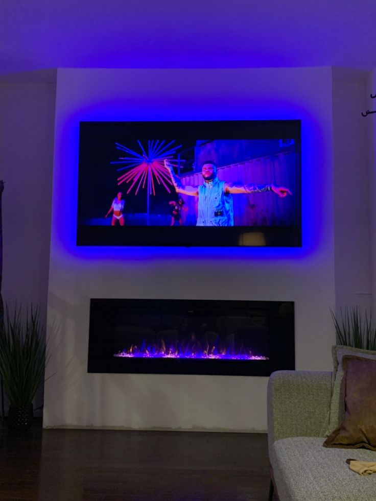 a living room with a large television mounted on the wall and a fire place in front of it