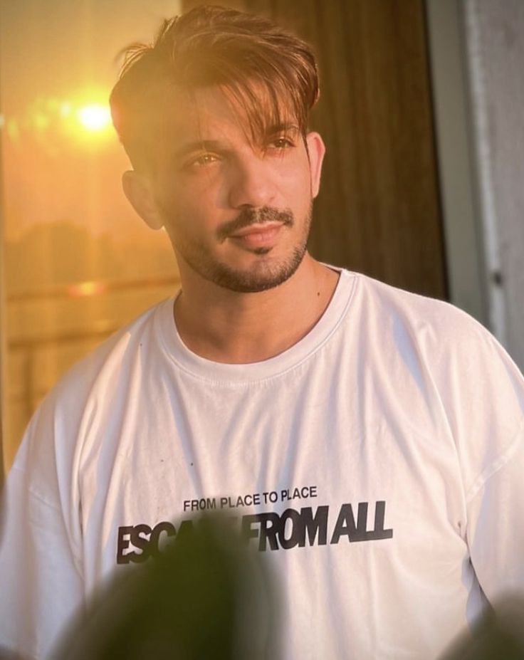 a man with a moustache standing in front of a door and looking at the camera