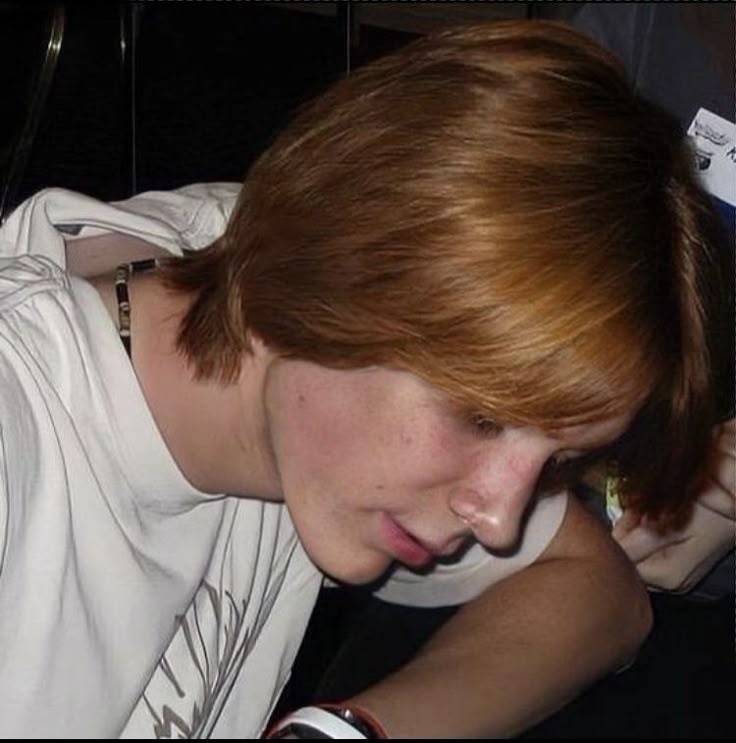 a young man is looking down at his cell phone