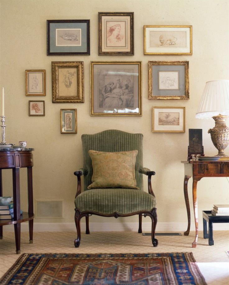 a living room filled with lots of framed pictures on the wall above a green chair