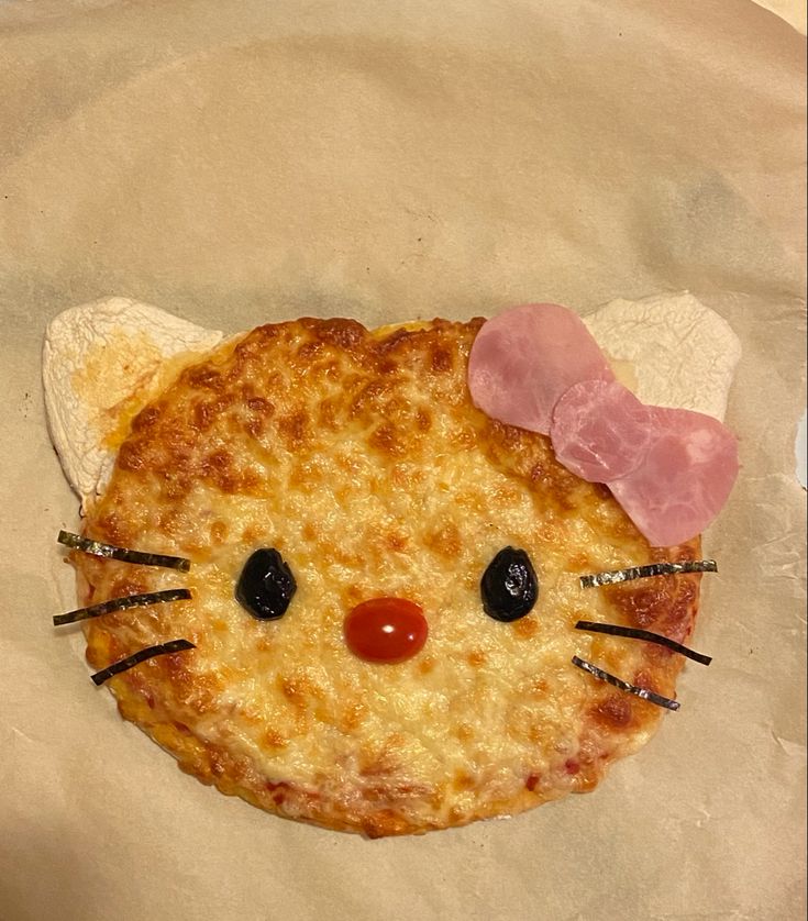 a pizza with a hello kitty face on it's side and a pink bow around its head