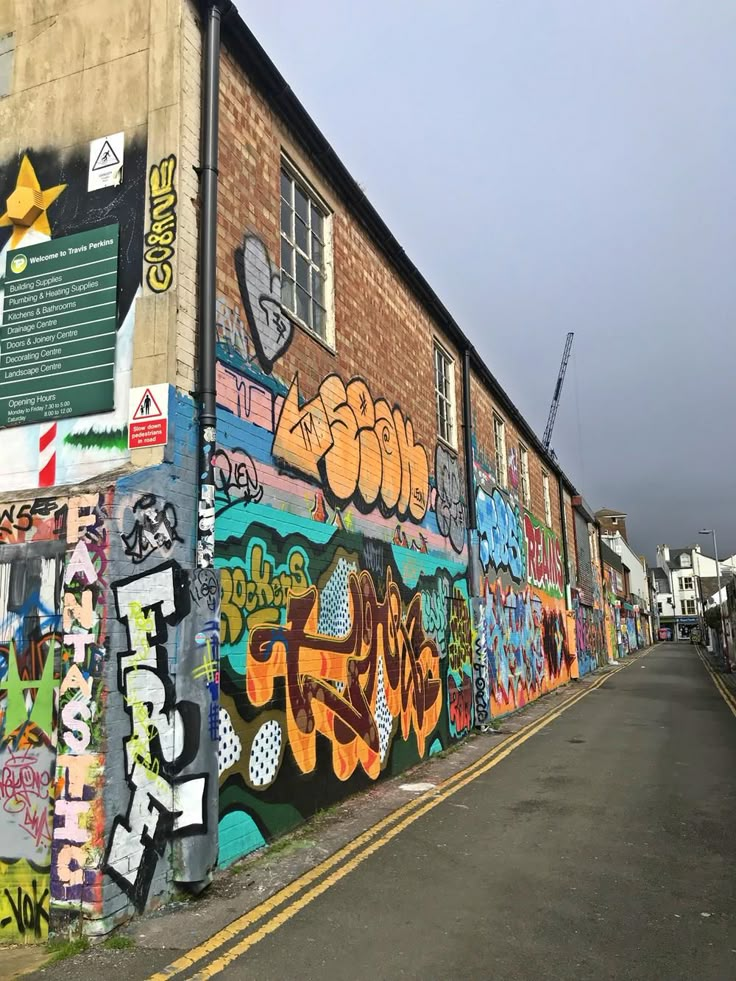 the side of a building with graffiti all over it's walls and sidewalk next to an empty street