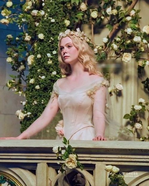 a woman standing on top of a balcony next to white flowers and greenery in the background