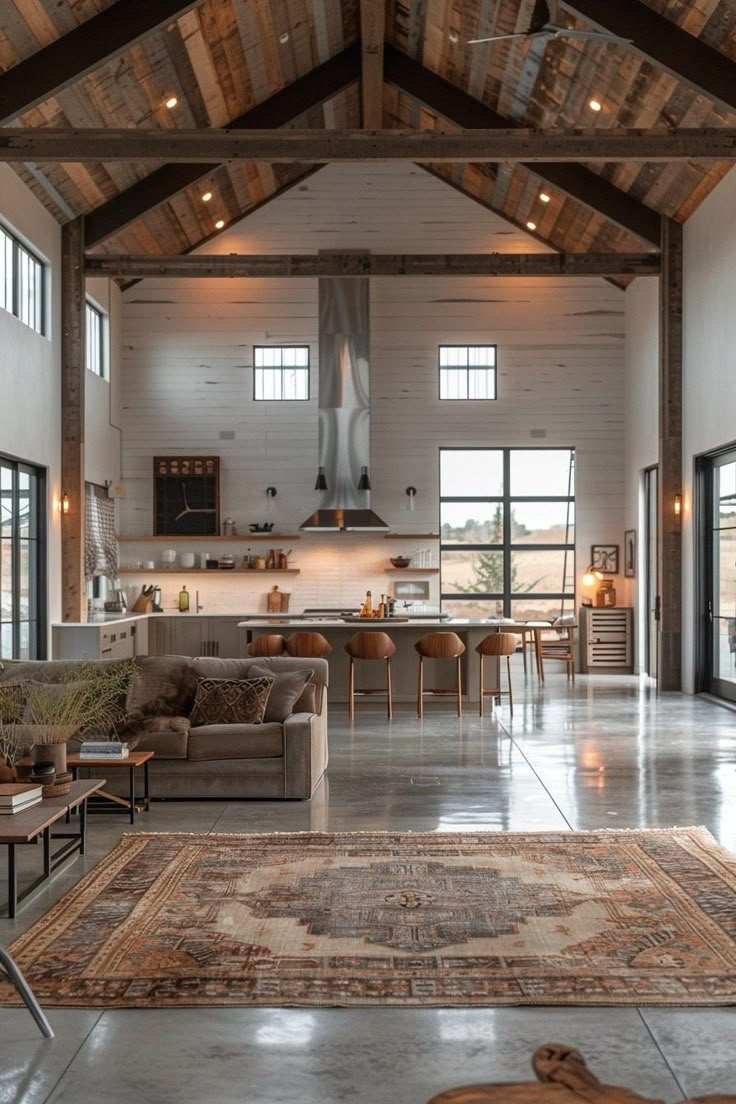 a large open living room with high ceilings and wooden beams on the ceiling, along with an area rug