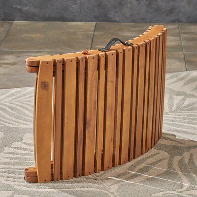 a wooden slatted bench sitting on top of a floor next to a wall