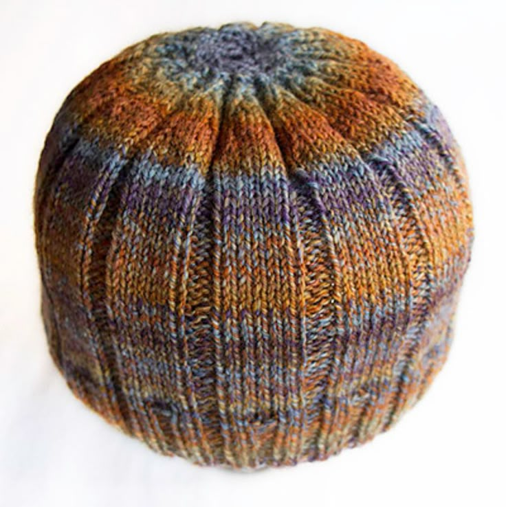 a multicolored knitted hat sitting on top of a white surface