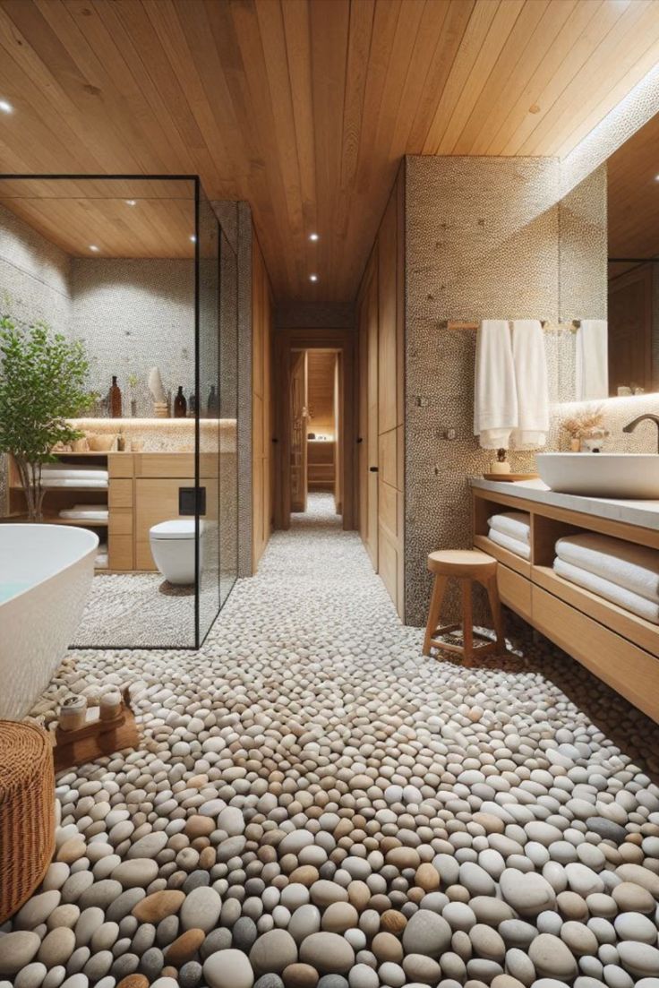 a large bathroom with rocks on the floor and wood paneled walls, along with a white bathtub