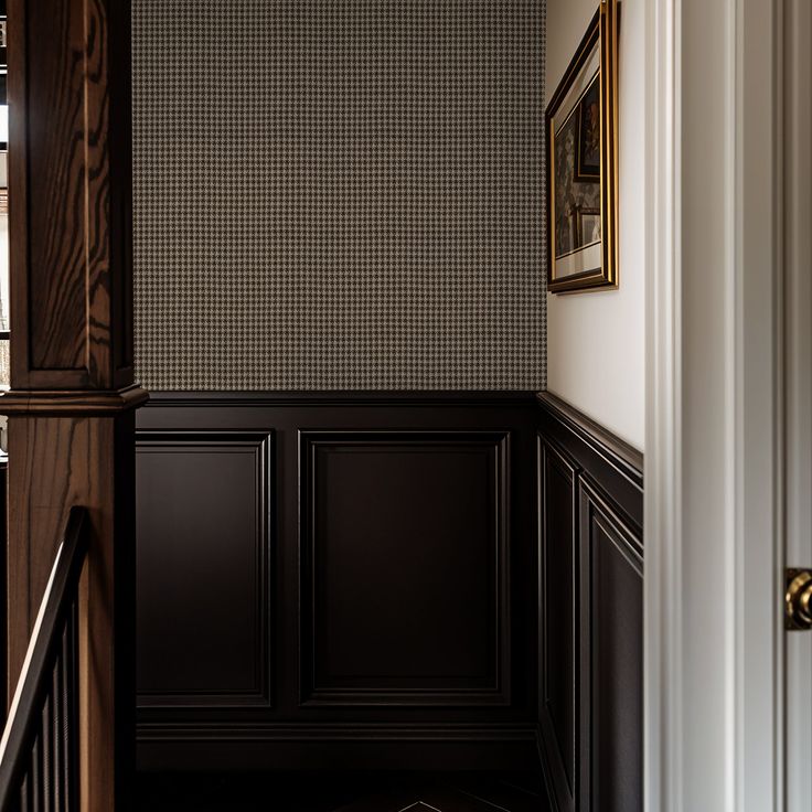 the hallway is decorated in black and white checkered wallpaper, along with wood paneling