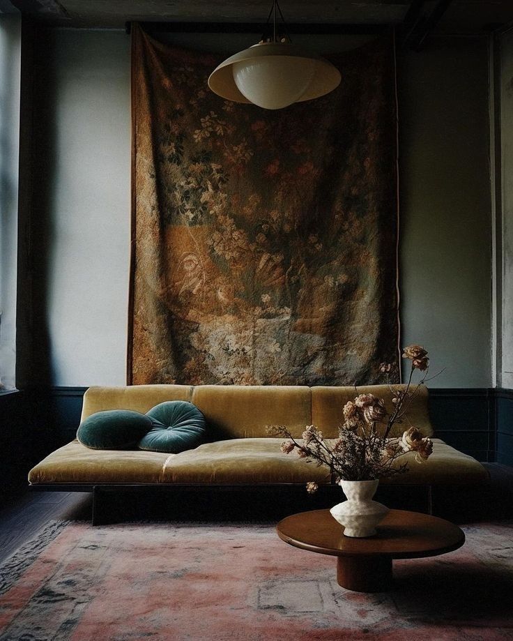 a living room with a couch, coffee table and tapestry on the wall behind it