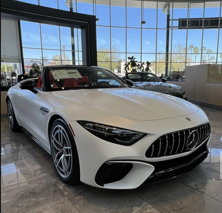 a white sports car is parked in front of some large windows and glass doors on the building