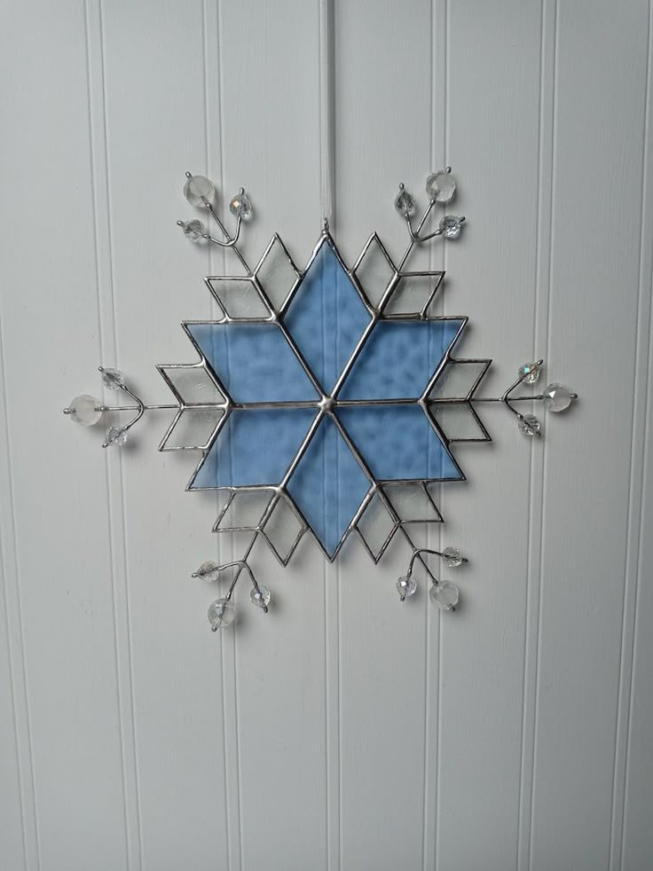 a blue snowflake hanging on the side of a white wall next to a door