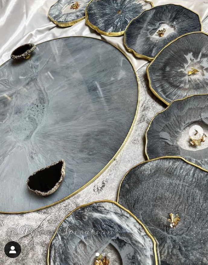 an assortment of decorative plates with gold trimmings and designs on the edges, sitting on a silver surface