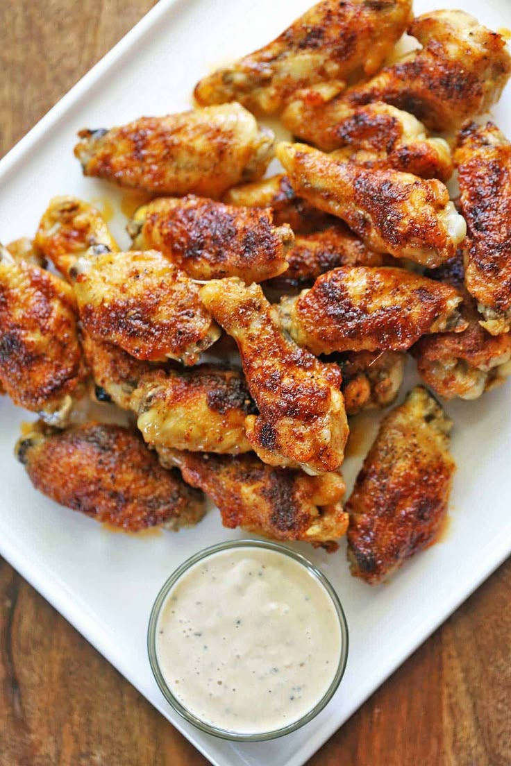 crispy baked wings on a white plate with ranch dressing in the background and text overlay that reads crispy baked wings