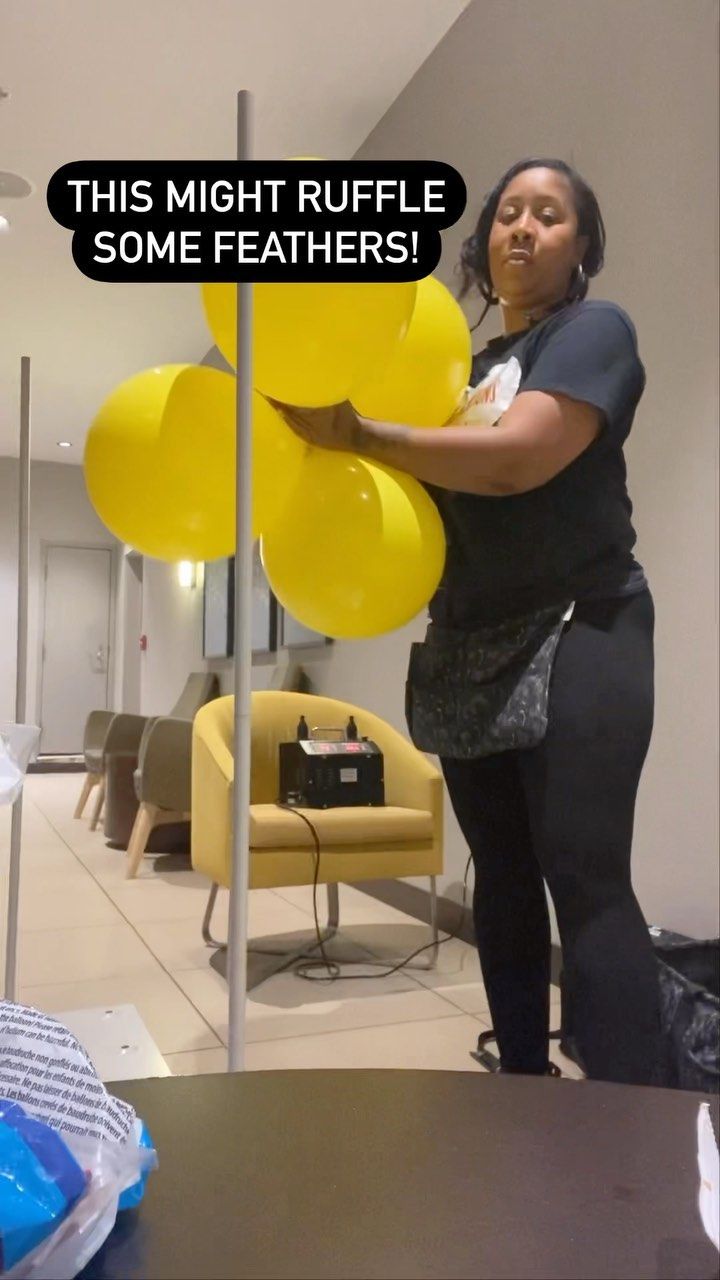 a woman holding yellow balloons in her hand and standing next to a sign that says, this might ruffle some feathers