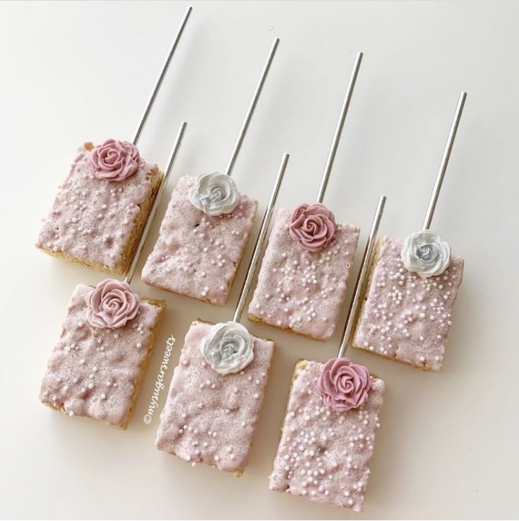 six square cakes with pink frosting and flowers on them, sitting next to each other