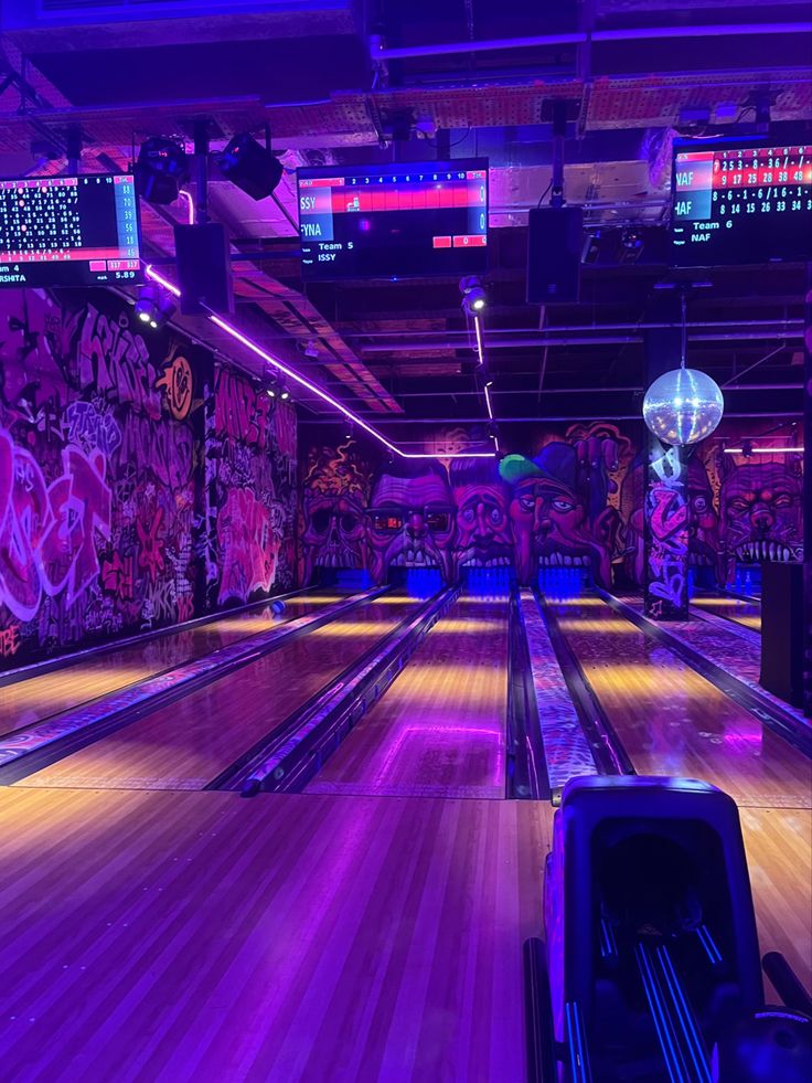 a bowling alley with neon lights and graffiti on the walls, along with several bowling lanes