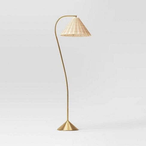 a floor lamp with a white shade on it's side and a gold base