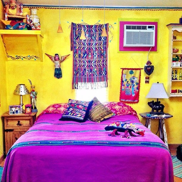 a bedroom with yellow walls and purple bedspread on the bed is decorated in mexican style