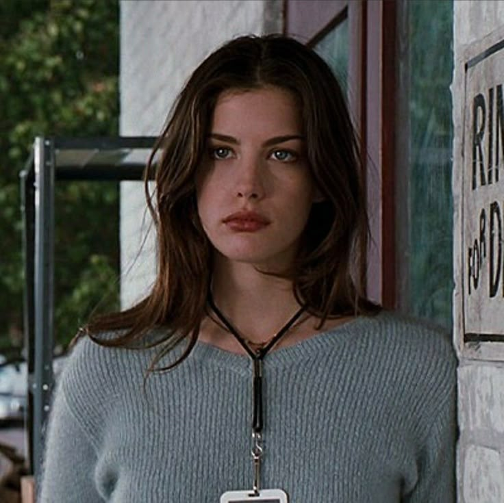 a woman standing in front of a window holding a cup and looking at the camera