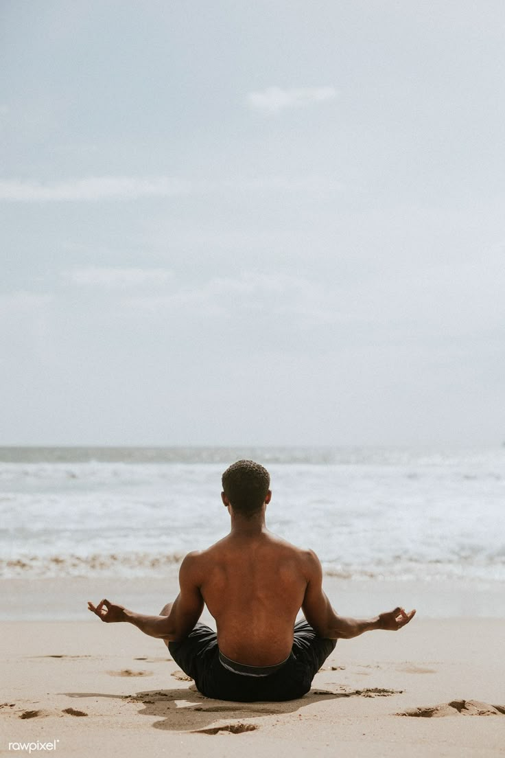 a man sitting on the beach doing yoga