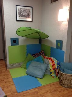 a child's bedroom with a green umbrella over the bed and blue sheets on the floor