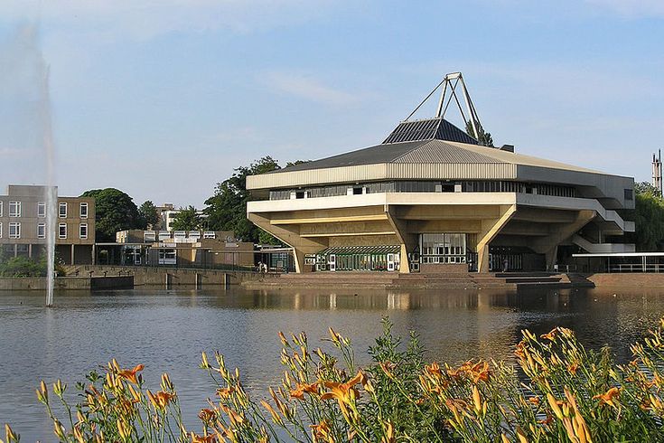 a large building sitting on the side of a river next to a lush green field