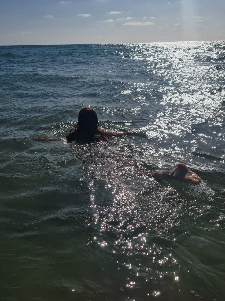 a person swimming in the ocean with their head above the water's surface and back to the camera