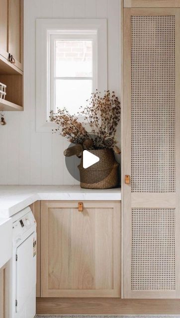 a kitchen with white walls and wooden cabinets, an open door leading to a window